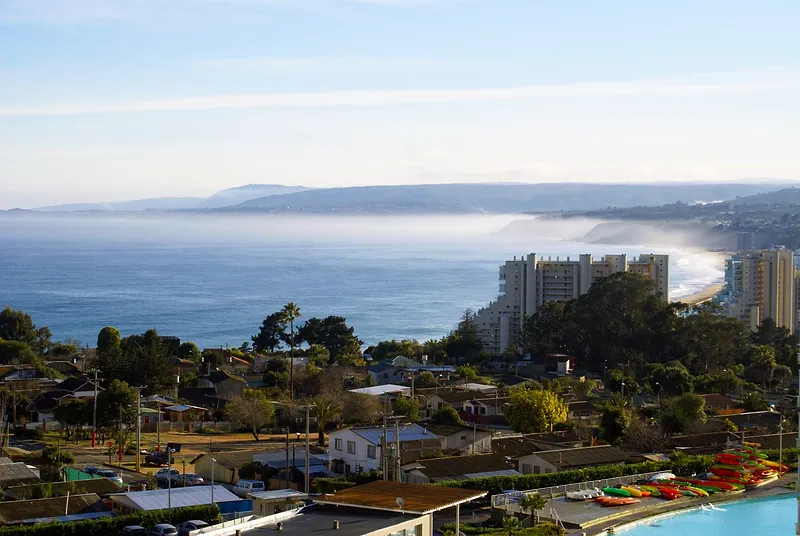 Algarrobo: casas entre árboles, edificios frente a la playa y la costa con neblina