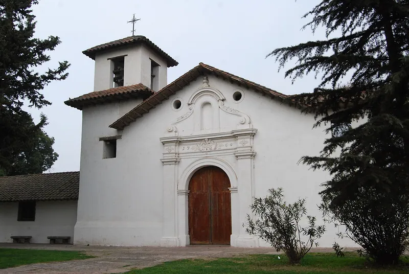 Fachada blanca de la Iglesia de los Jesuitas de Calera de Tango, con su campanario y su portón de madera