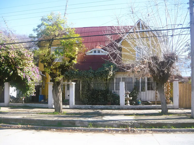 Casa antigua de dos pisos, de fachada amarilla y techo rojo, detrás de una reja en el centro de Graneros