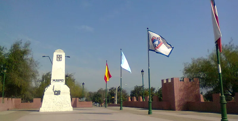 Monumento al Abrazo de Maipú: obelisco blanco con la inscripción «1818 Maipo», banderas y muros almenados