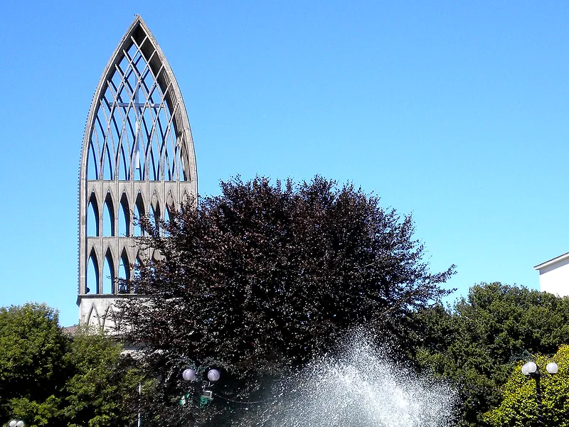 Torre de la catedral de San Mateo de Osorno vista desde la Plaza de Armas, con árboles y el chorro de una pileta