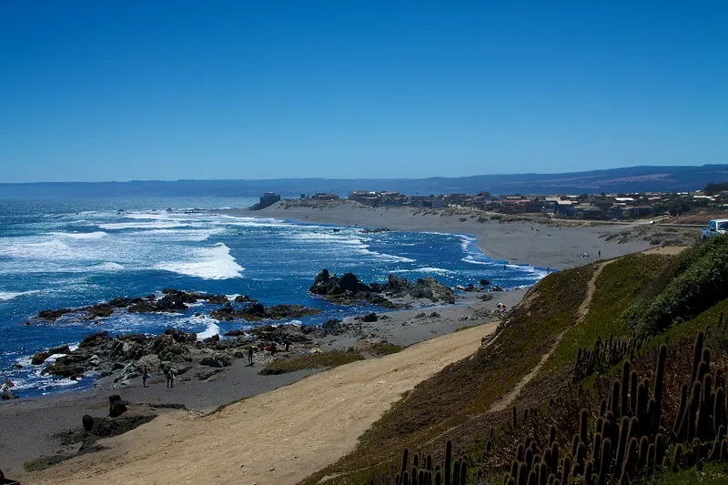 Costa de Pichilemu: roqueríos, playa y oleaje, con el pueblo al fondo