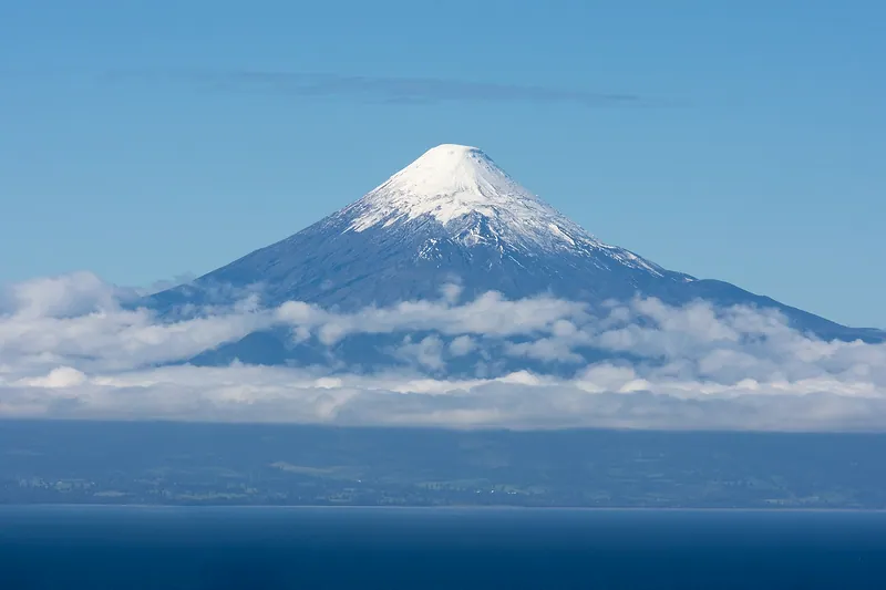 Volcán Osorno nevado sobre el lago Llanquihue, con nubes bajas
